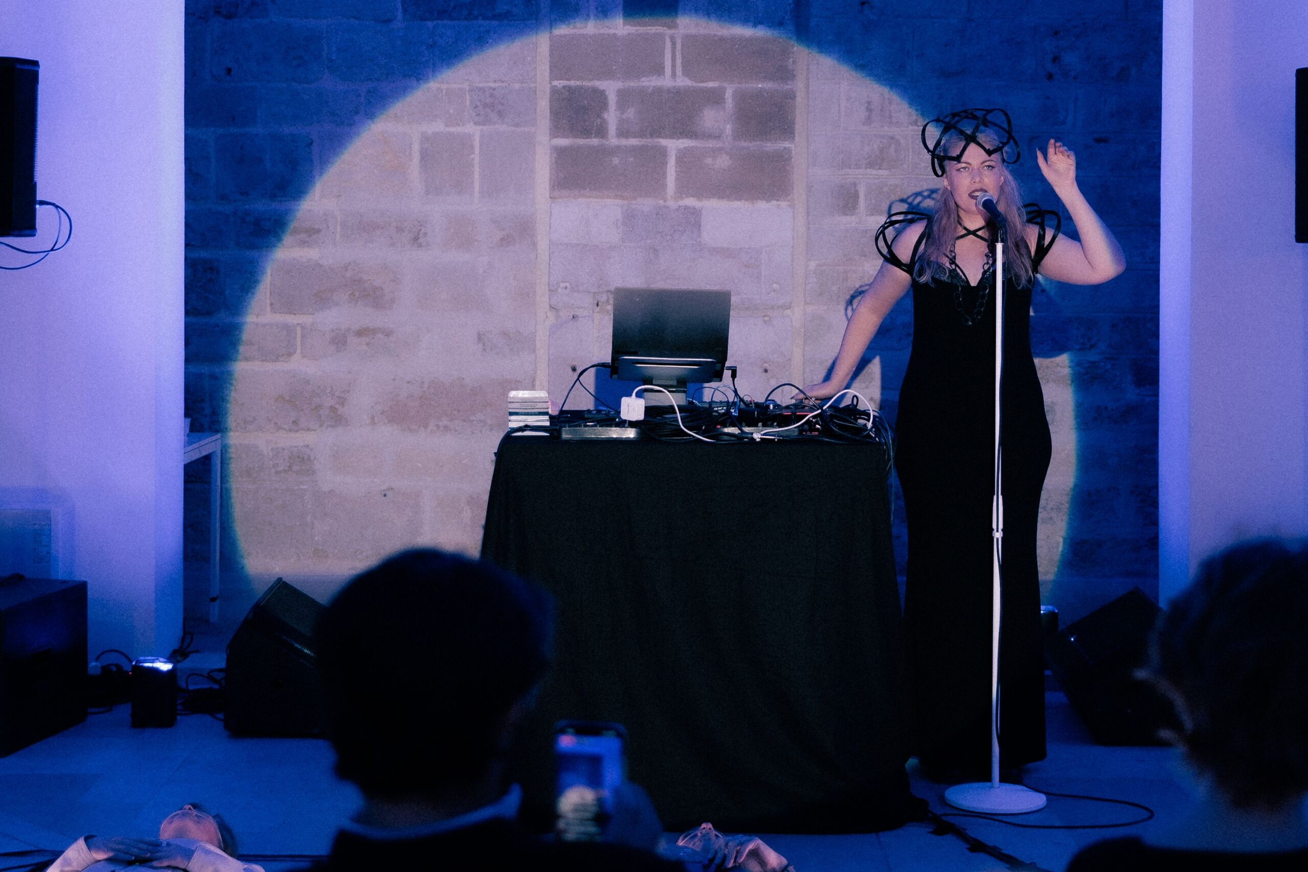 a woman in a long black dress by a microphone singing in a spotlight
